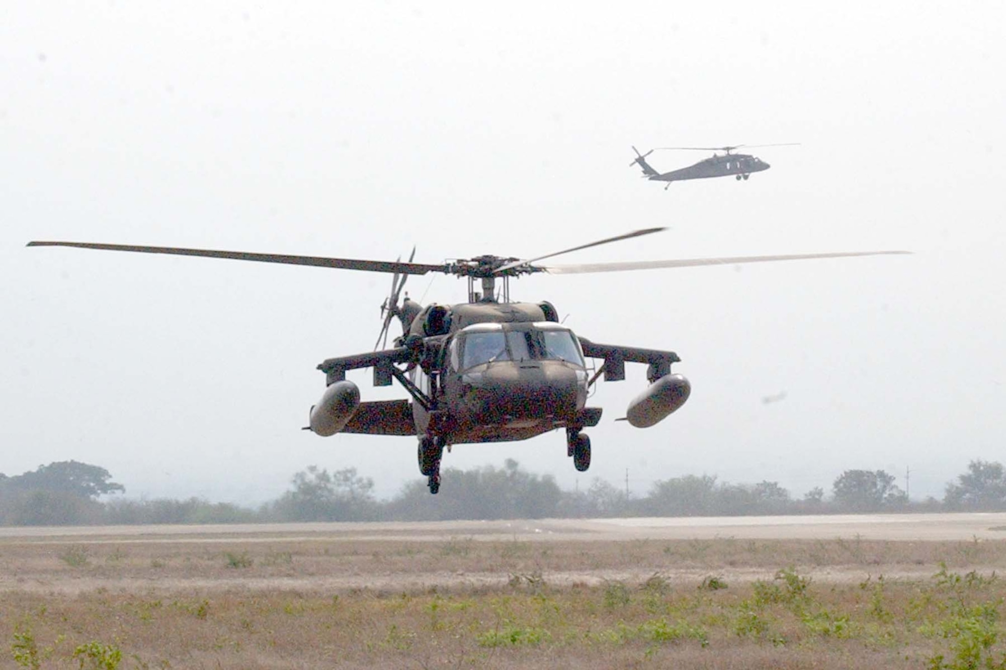 SOTO CANO AIR BASE, REPUBLIC OF HONDURAS -- A 1-228th Aviation Regiment Blackhawk helicopter is marshalled in to the Forward Aerial Refueling Point (FARP) set up this week to train helicopter aircrew and POL Soldiers on proper 'hot' refueling procedures with FARP equipment, while another waits in the background for it's opportunity to refuel. (U.S Air Force photo by Staff Sgt. Chyenne A. Griffin) 