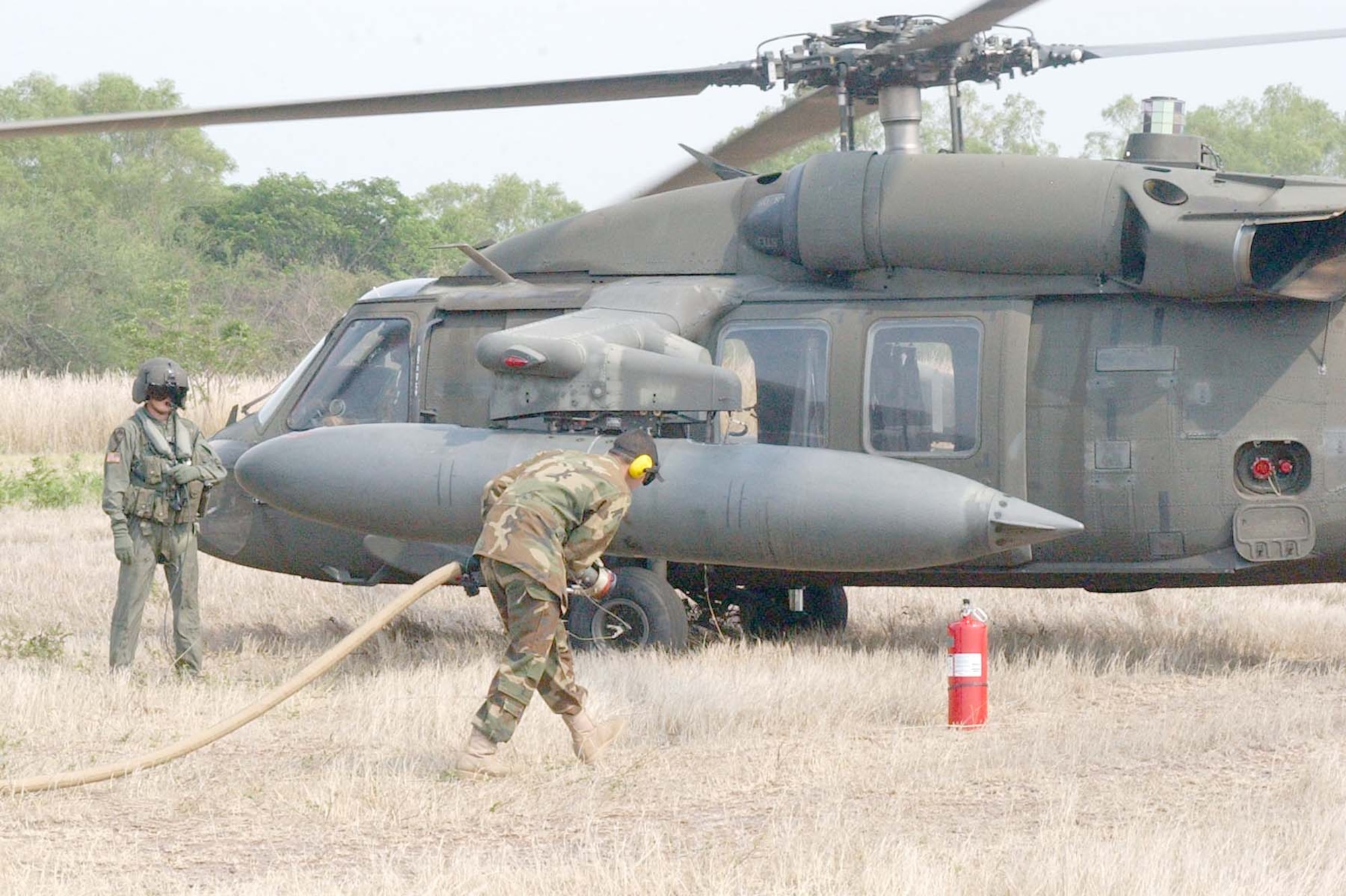 SOTO CANO AIR BASE, REPUBLIC OF HONDURAS -- Army Spc.Gregory Luna, 1-228 Aviation Regiment Petroleum, Oil and Lubricants (POL) section, runs the fuel line out to a waiting Blackhawk helicopter for a 'hot' refuel during Forward Aerial Refueling Point (FARP) training held this week to train POL Soldiers and helicopter aircrew members. (U.S Air Force photo by Staff Sgt. Chyenne A. Griffin) 