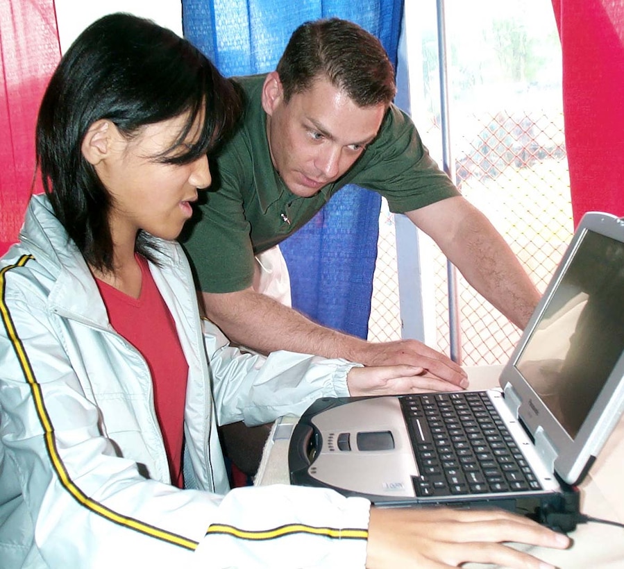 Edith Yu of Dublin, Ohio, adds her name to a  virtual "America's Thank You Note" at the DefendAmerica  information booth May 9, 2002, in the Public Service  Recognition Week exhibit on Washington's National Mall.  James Flouhouse of the Department of Defense public affairs  office gives her a hand. The note expresses thanks and  appreciation to the men and women of the U.S. military.  Other exhibit visitors can sign up through May 12. People  also can submit "America's Thank You Notes" at  href="http://defendamerica.mil/nmam.html DefendAmerica Web site at www.defendamerica.gov through May 31. The names  will be gathered and presented to the military at the end  of the month. Photo by Gerry J. Gilmore.