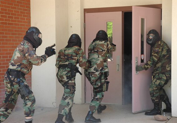 Senior Airman Brian Batema (right) holds the door open for Staff Sgt. Joshua Sharloken, Staff Sgt. Waylon Mitchell and Tech. Sgt. Jeff Ward, all from the 355th Security Forces Squadron here, so they can quickly enter the cafeteria and confront a hostile gunman during a training exercise at Lowell H. Smith Middle School here April 19. Using paintball handguns,  trainers from the Tucson Police Department's Special Weapons and Tactics Team taught members of several law enforcement agencies how to respond to an armed assailant in a school setting. (U.S. Air Force photo/Staff Sgt. Jake Richmond)