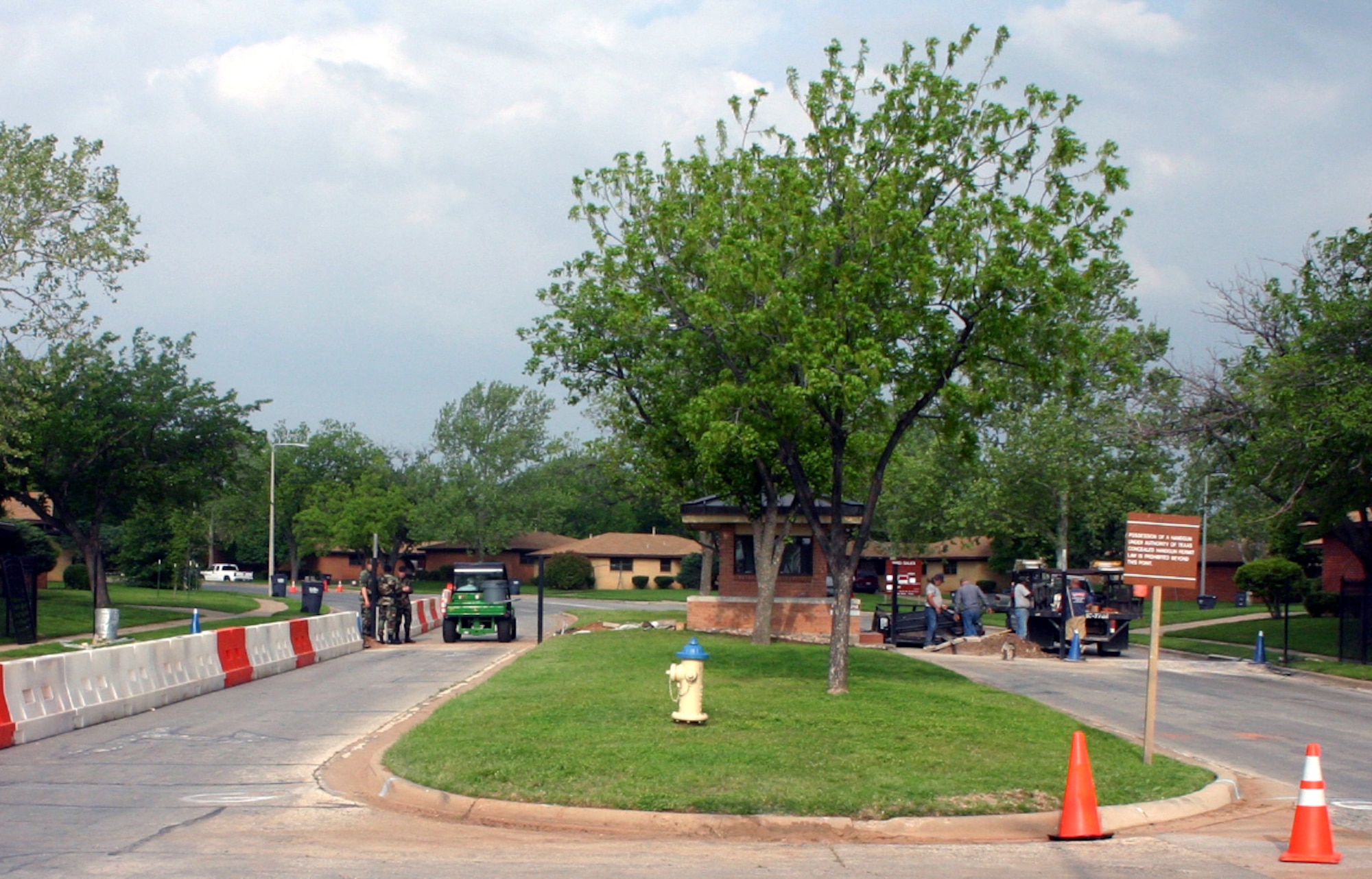 As construction workers install the keypad access terminal that will soon govern all entrance onto Capehart Housing premises, the last of the gate guards check ID's on a road that has been temporarily converted to a two-lane street. (U.S. Air Force photo/Staff Sgt. Tonnette Thompson)