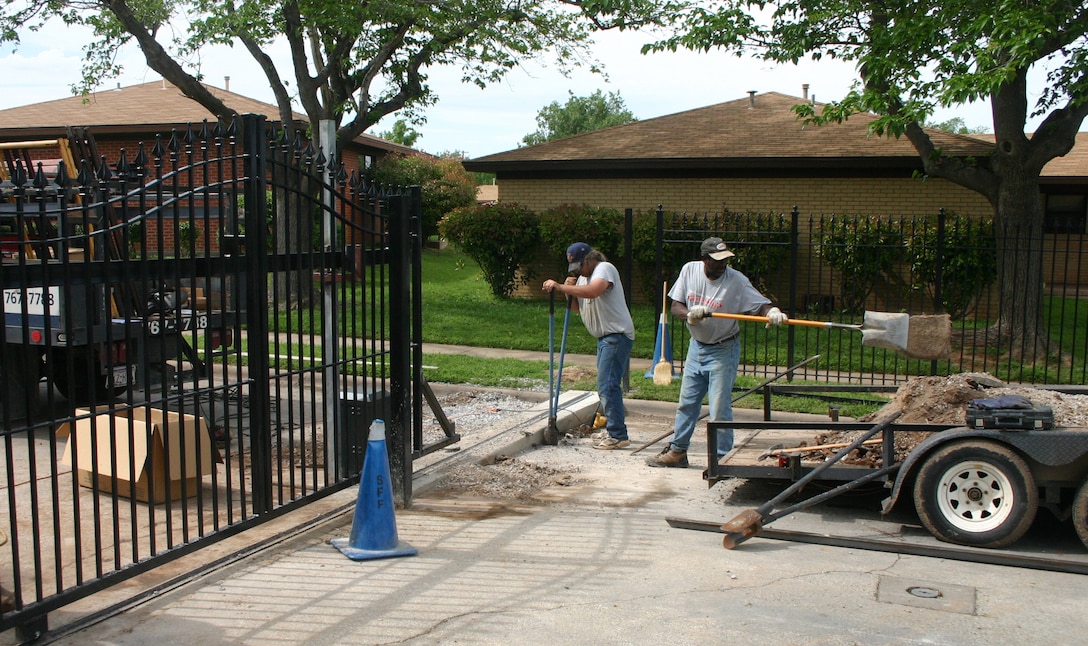 John Smith (left) and Buddy Love, employees of Overhead Door/Price Fencing Wichita Falls, post holes and clear rubble for Capehart Housing's new gate April 24. (U.S. Air Force photo/Staff Sgt. Tonnette Thompson)
