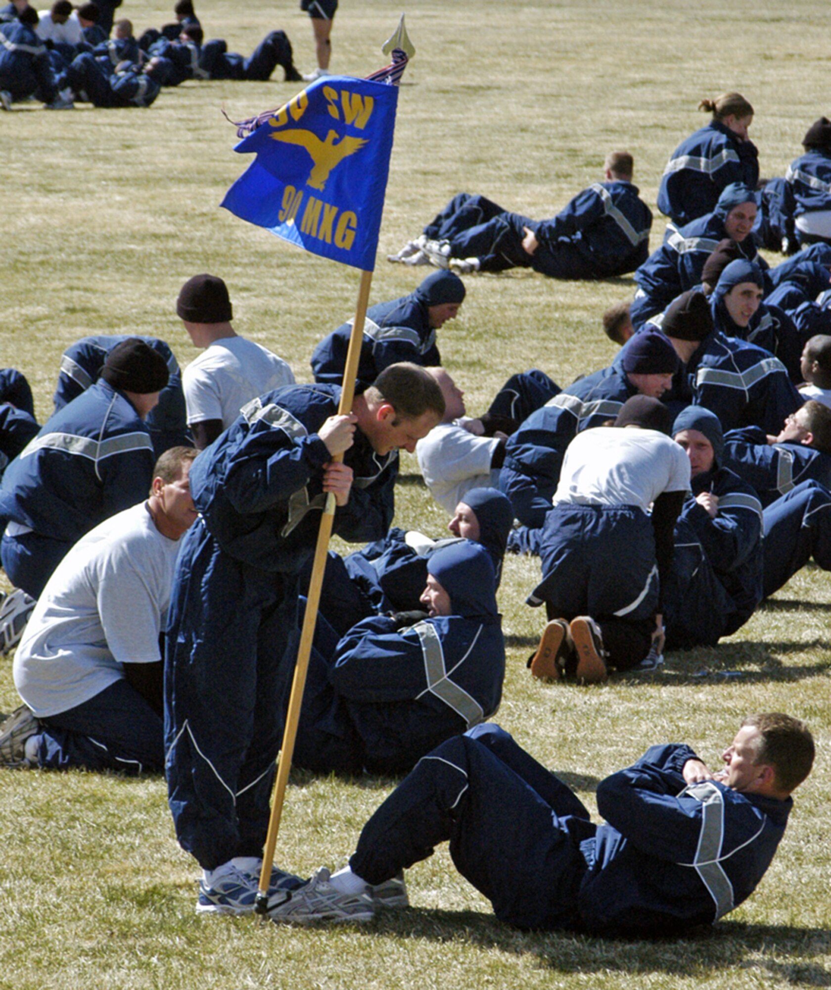 Members of the 90th Maintenance Group help each other during the calisthenics phase of the wing run April 11. Participants ran through a variety of weather challenges including cool temperatures to start, warm temperatures towards the end and gusty winds that helped encourage runners to finish faster (Photo by Staff Sgt. Kurt Arkenberg).