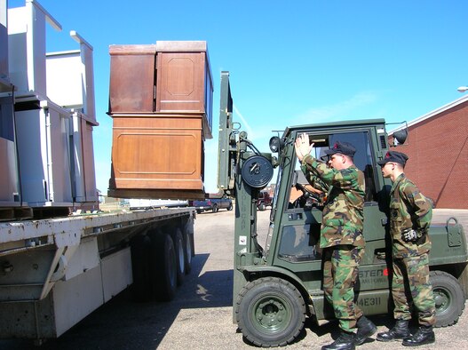 Three 90th Logistic Readiness Squadron Airmen guide office furniture from Bldg. 332 onto a flat bed truck recently. Furniture not taken by other agencies had to be moved out by the 90th LRS (Courtesy photo).