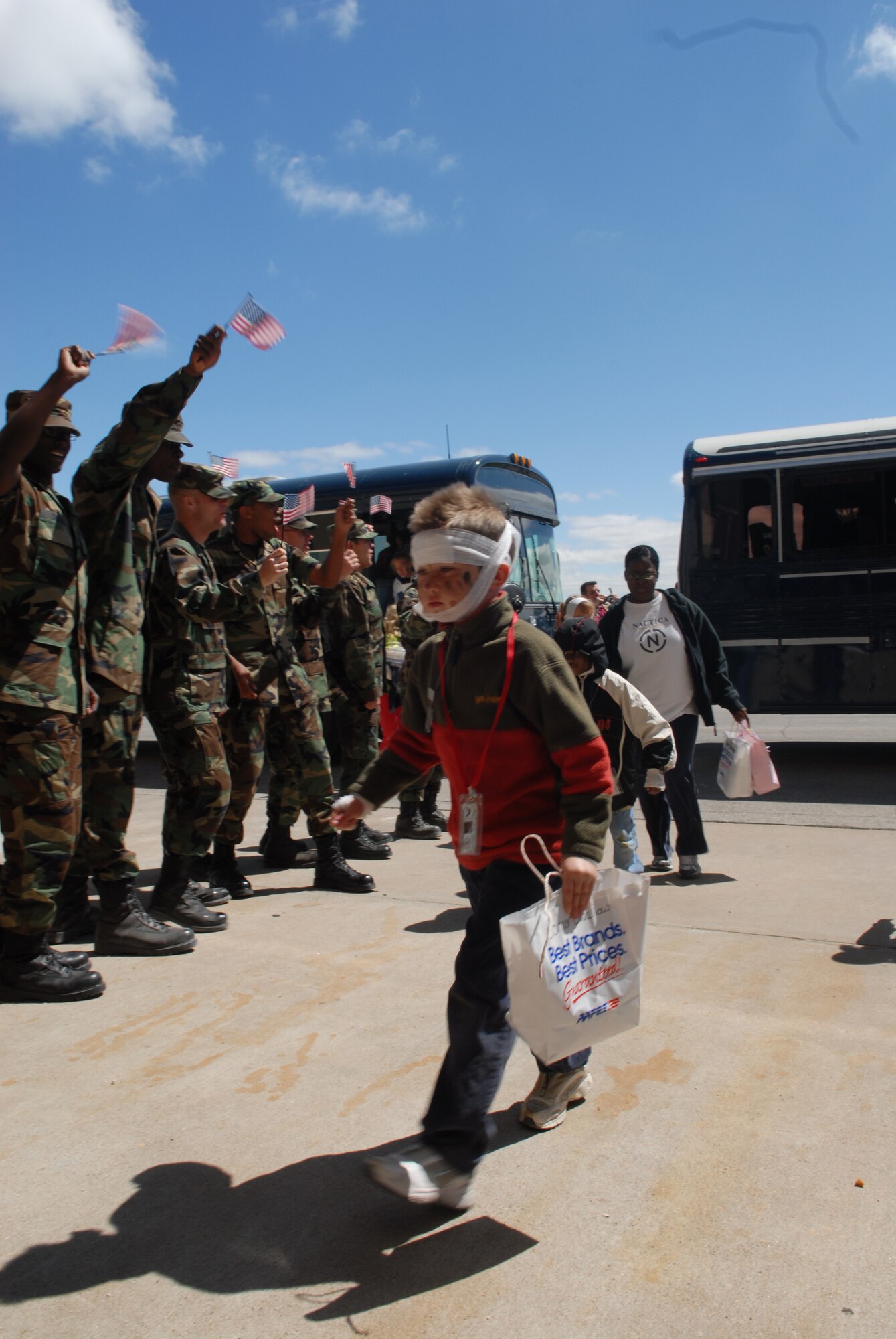 As proud as any servicemember, a tired Connor Swallow returns home to thunderous applause and a line of Airmen waving flags. The bandages on his head are from the moulage activity at Discovery Air Base, where volunteers from the 17th Medical Group   applied mock injuries to the deployees. (U.S. Air Force photo by Airman 1st Class Kamaile Chan)