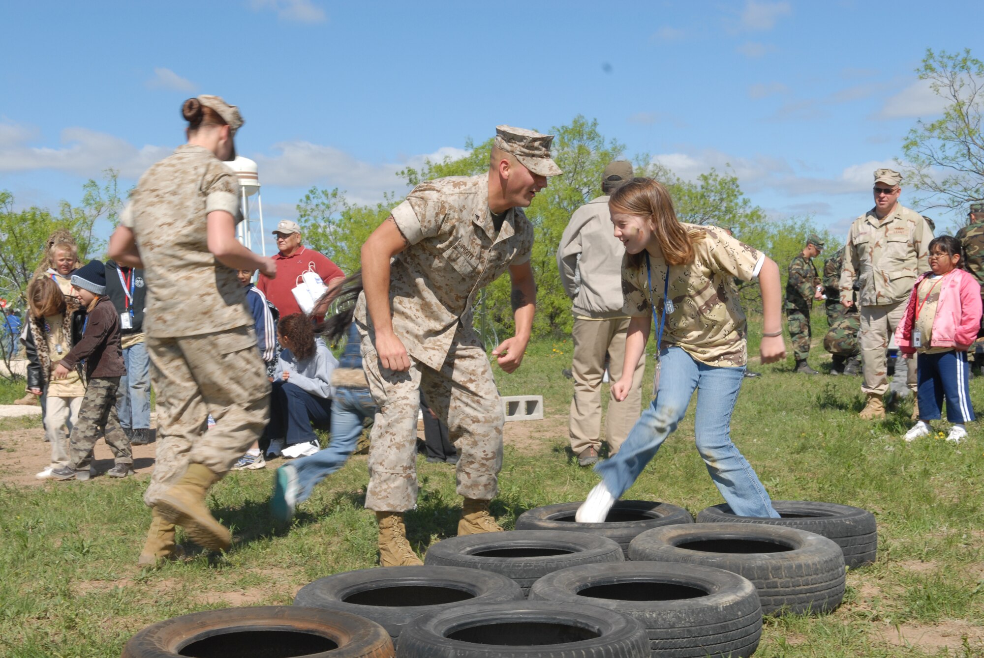 Lance Cpl. William Pigott, an Operation KIDS volunteer assigned to Marine Corps Detachment Goodfellow, motivates Morgan Thrush as she navigates the obstacle course Saturday. The obstacle course was just one of the activities at Discovery Air Base, a mock tent city set up at Goodfellow’s Camp Sentinel exercise site. Airmen, Soldiers, Sailors and Marines all volunteered to help with the event. (U.S. Air Force photo by Airman 1st Class Kamaile Chan)