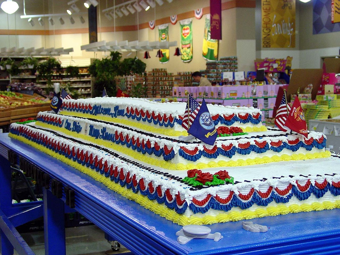 A giant homecoming cake made by the Naval Air Station Oceana Commissary contract baker sits in the store display area nearly finished. A top tier shaped like an aircraft carrier still needs to be added. The 750-pound cake, with a footprint of 36 square feet, would feed about 2,500 people. It was made for the crew of the aircraft carrier USS Theodore Roosevelt and their families, who celebrated the ship's return to homeport, Naval Station Norfolk, Va., March 27, 2002, from Operation Enduring Freedom. DoD photo.