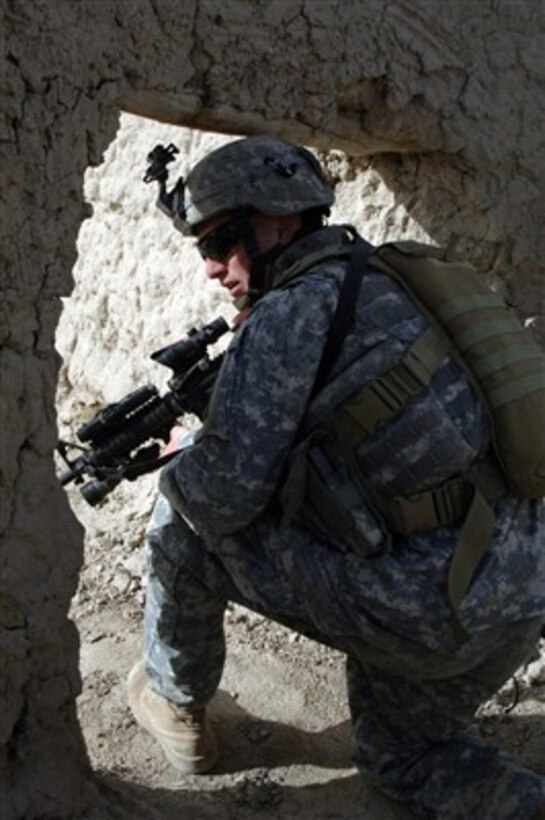 U.S. Army Spc. Adam Miller provides security through a narrow doorway on a route reconnaissance mission near Mir-e, Afghanistan, on April 5, 2007.  Miller is assigned to Headquarters and Headquarters Company, 2nd Battalion, 508th Parachute Infantry Regiment.  