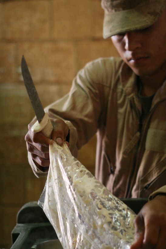 COMMAND OUTPOST NORSEMAN, RUTBAH, Iraq ? Lance Cpl. Rene M. Cruzhernandez, a food service specialist with Task Force Tarawa, empties a bag of shrimp scampi into a heated serving pan.