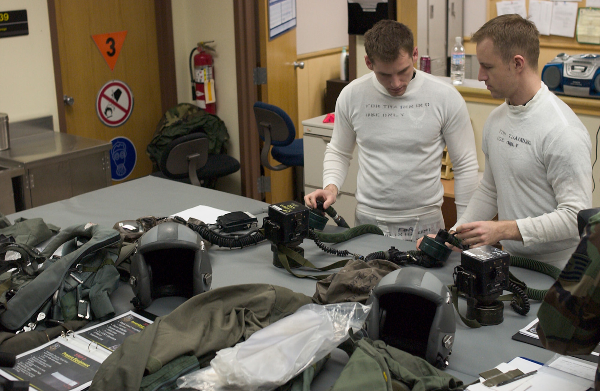 KUNSAN AB, Republic of Korea -- 1st Lt Mathew Olson and 1st Lt Trevor Callens prepare to don Aircrew Eye Respiratory Protection System during an operational readiness inspection here April 16.  Both are F-16 pilots with the 80th Fighter Squadron. All aircrew members stop at the 80th Life Support Section to check out their equipment prior to their flight. Their lives depend on the serviceability and operability of the equipment and the Life Support Section?s primary mission is to ensure the equipment is ready. The 8th Fighter Wing is currently undergoing an ORI to test its ability to conduct its wartime mission. (U.S. Air Force Photo by Senior Airman Barry Loo.)