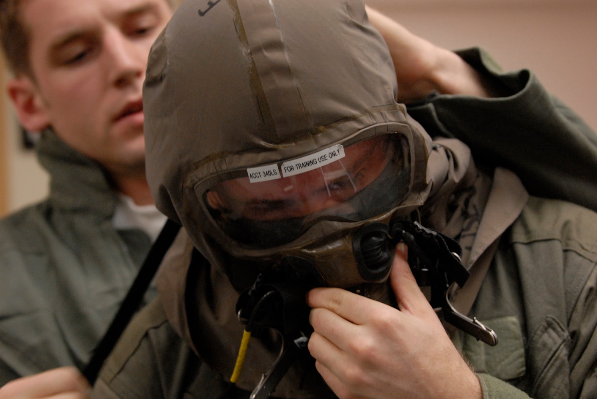 KUNSAN AB, Republic of Korea -- 1st Lt Mathew Olson, back, assists 1st Lt Trevor Callens don an Aircrew Eye Respiratory Protection System during an operational readiness inspection here April 16.  Both are F-16 pilots with the 80th Fighter Squadron. All aircrew members stop at the 80th Life Support Section to inspect their equipment prior to their flight. Their lives depend on the serviceability and operability of the equipment and the Life Support Section?s primary mission is to ensure the equipment is ready. The 8th Fighter Wing is currently undergoing an ORI to test its ability to conduct its wartime mission. (U.S. Air Force Photo by Senior Airman Barry Loo.)