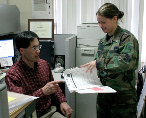 Mr. Yoshikatsu Nakamura provides guidance to Airman 1st Class Amanda Hildreth. Mr. Nakamura won the Civilian of the Year based on his contributions to the success of his unit. The contractor was presented the 5th Air Force level award on April 11. (U.S. Air Force photo by Staff Sgt. Vann Miller)