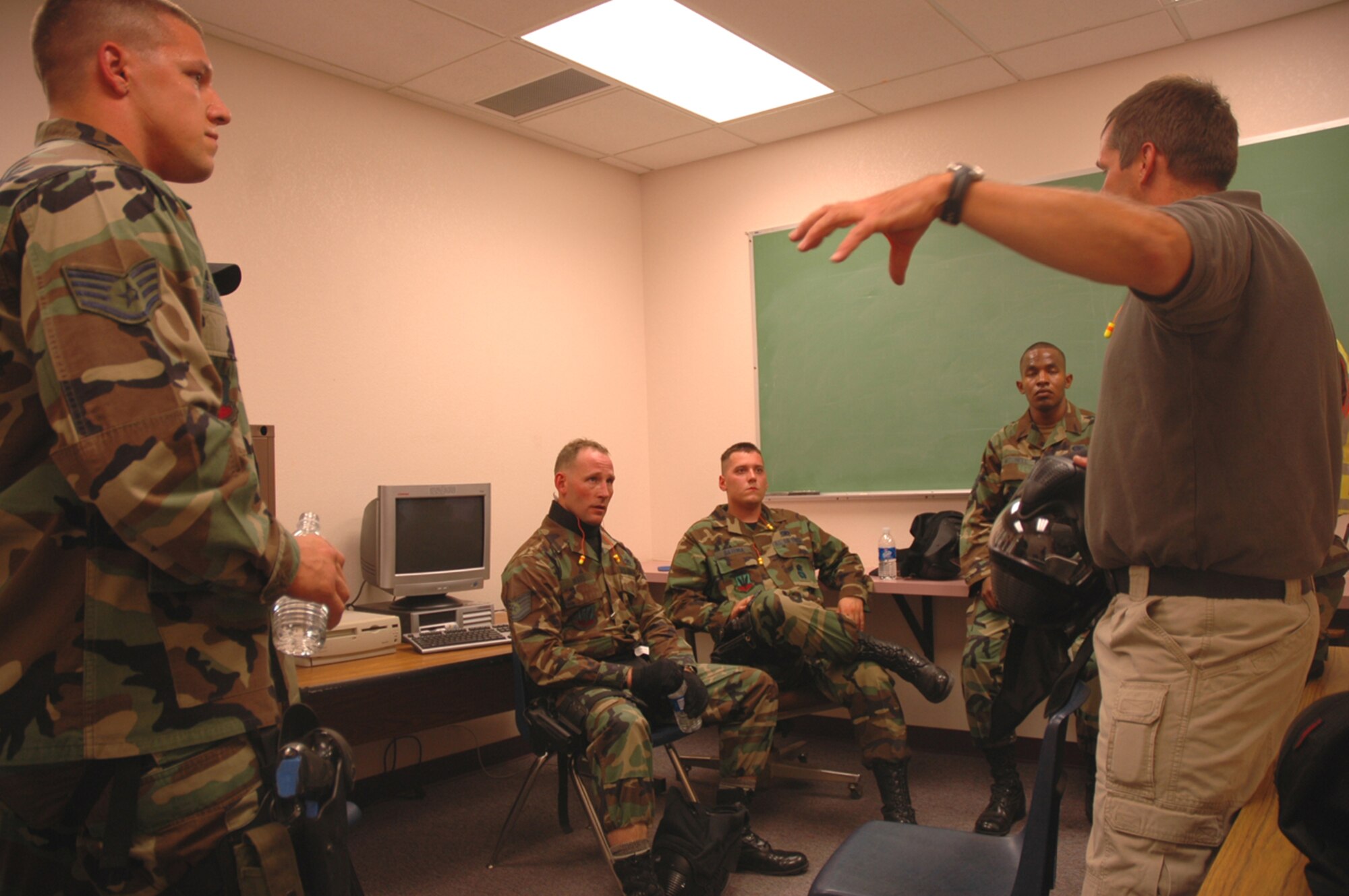 Mr. Kevin Johnson (right), a trainer for the 355th Security Forces Squadron here, conducts a post-exercise training briefing April 19 with Staff Sgt. Waylon Mitchell, Senior Airman Brian Batema, Tech. Sgt. Jeff Ward and Staff Sgt. Joshua Sharloken, all from the 355th SFS. Trainers from the Tucson Police Department's Special Weapons and Tactics Team came to Lowell H. Smith Middle School here and taught members of several law enforcement agencies how to respond to an armed assailant in a school setting. (U.S. Air Force photo/Staff Sgt. Jake Richmond)