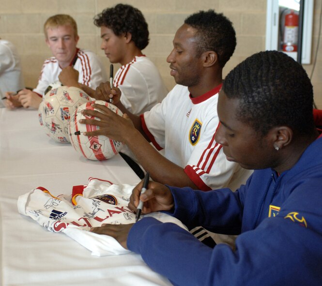 Real Salt Lake player Freddy Adu autographs a shirt while fellow team members (left to right), Christian Jimenez and Jeff Cunningham sign soccer balls for fans during the Salute to Team Hill held at the base fitness center. Photo by Alex R. Lloyd