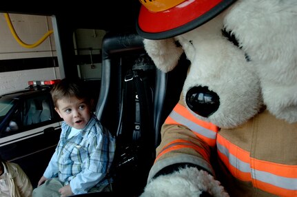 Zachary Moore, 3, son of Capt. Christopher Moore, 437th Airlift Wing chief of public affairs, sits next to Sparky in a fire truck during his tour of the Charleston AFB fire station.  Zachary was honored in Charleston's Pilot for a Day program April 20.(United States Air Force photo by Airman 1st Class Nicholas Pilch)