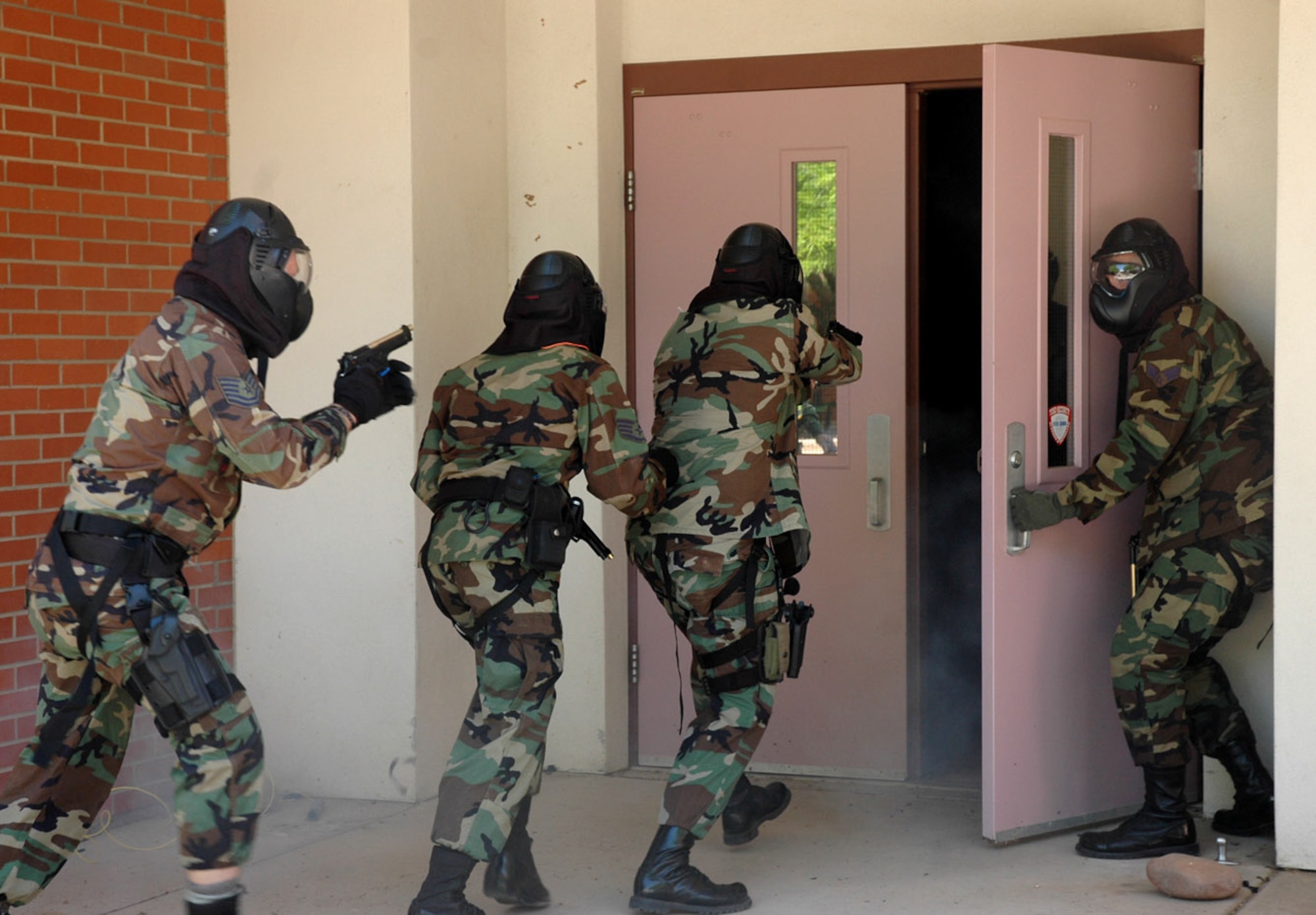 Senior Airman Brian Batema (right) holds the door open for Staff Sgt. Joshua Sharloken, Staff Sgt. Waylon Mitchell and Tech. Sgt. Jeff Ward during a security exercise conducted by Tucson Police Department special weapons and tactics team trainers April 25 at a local middle school.  The Airmen, from the 355th Security Forces Squadron at nearby Davis-Monthan Air Force Base, joined members of several local law enforcement agencies to train on how to respond to an armed assailant at a school.  (U.S. Air Force photo/Staff Sgt. Jake Richmond)