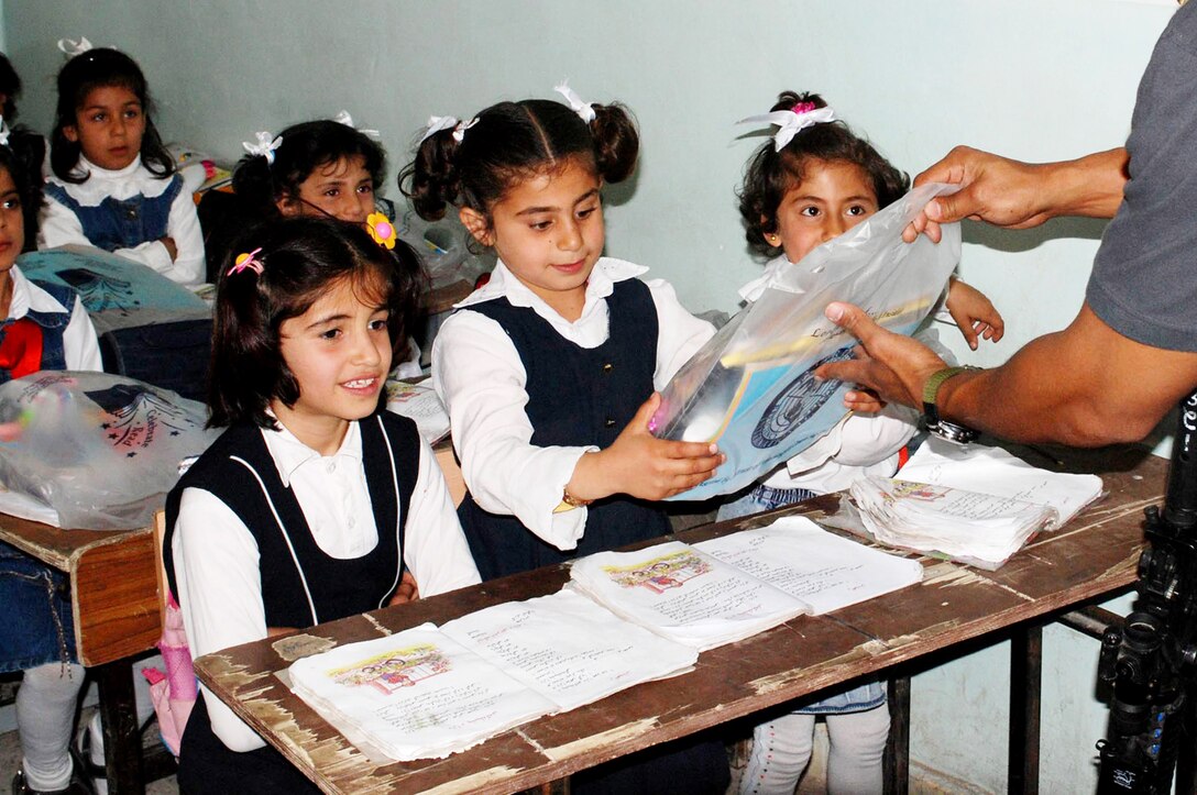 An agent from the Air Force Office of Special Investigations Expeditionary Detachment 2410 at Kirkuk Air Base, Iraq, hands out bags of school supplies to children at a nearby school April 18. This effort is part of Operation Iraqi School Supplies, and is sponsored by the 506th Air Expeditionary Group. School supplies are sent from people all over the United States. (U.S. Army photo/Spc. Jaun Jimenez)