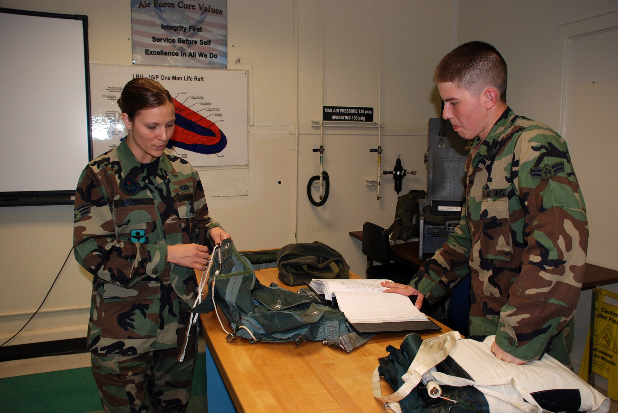 Senior Airman Cristy Aponte, an instructor with the 361st Training Squadron's Aircrew Life Support course, shows an Airman-in-Training the proper way to pack an ACE-2 survival bag April 20. (U.S. Air Force photo/Airman 1st Class Jacob Corbin)