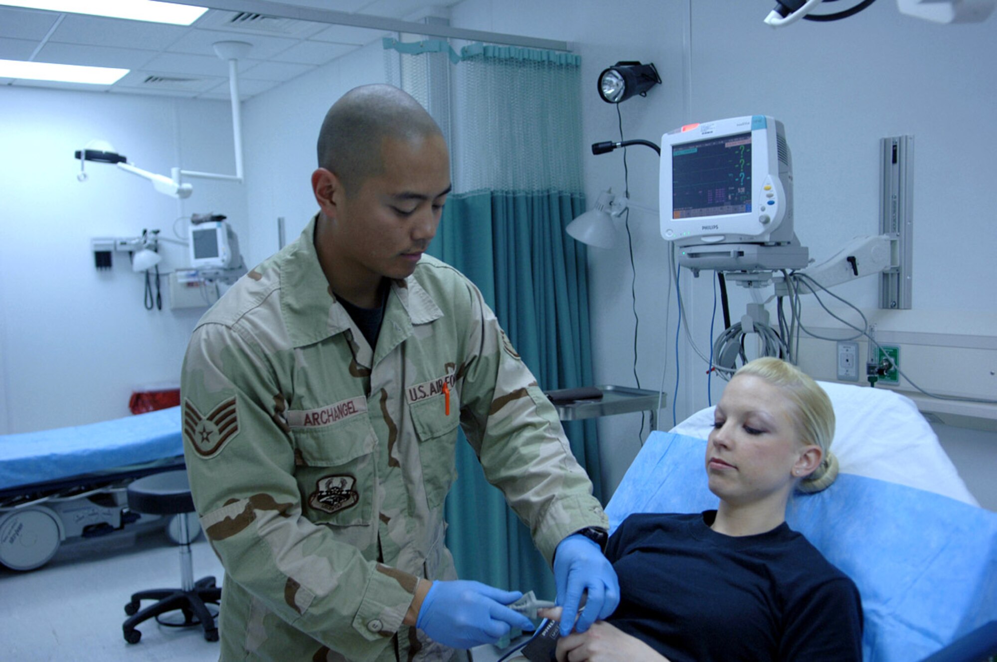 Staff Sgt. Joseph Archangel installs a pulse monitor on Senior Airman Nicole Moore's index finger April 12 during training at Bagram Air Base, Afghanistan. Both Airmen are emergency medical technicians assigned to Task Force Med at the new Craig Joint Theater Hospital. (U.S. Air Force photo/Staff Sgt. Kevin Tomko)