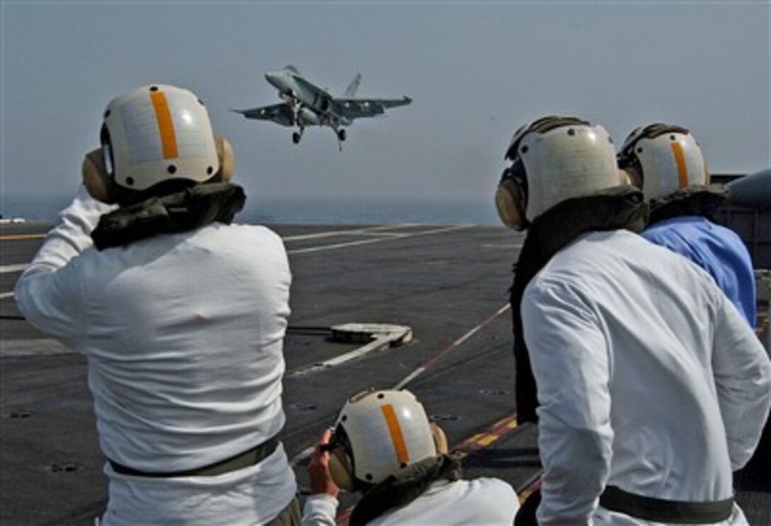 Joint Civilian Orientation Conference participants stand on the USS Eisenhower's flight deck to watch an F/A-18 aircraft land, April 25, 2007.