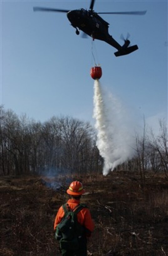 Mike Eilers guides a UH-60A Black Hawk helicopter crew from the Minnesota National Guard as it dumps water from a Bambi Bucket during firefighting training at Camp Ripley, Minn., on April 20, 2007.  Eilers is with the Forestry Division of the Minnesota Department of Natural Resources.  