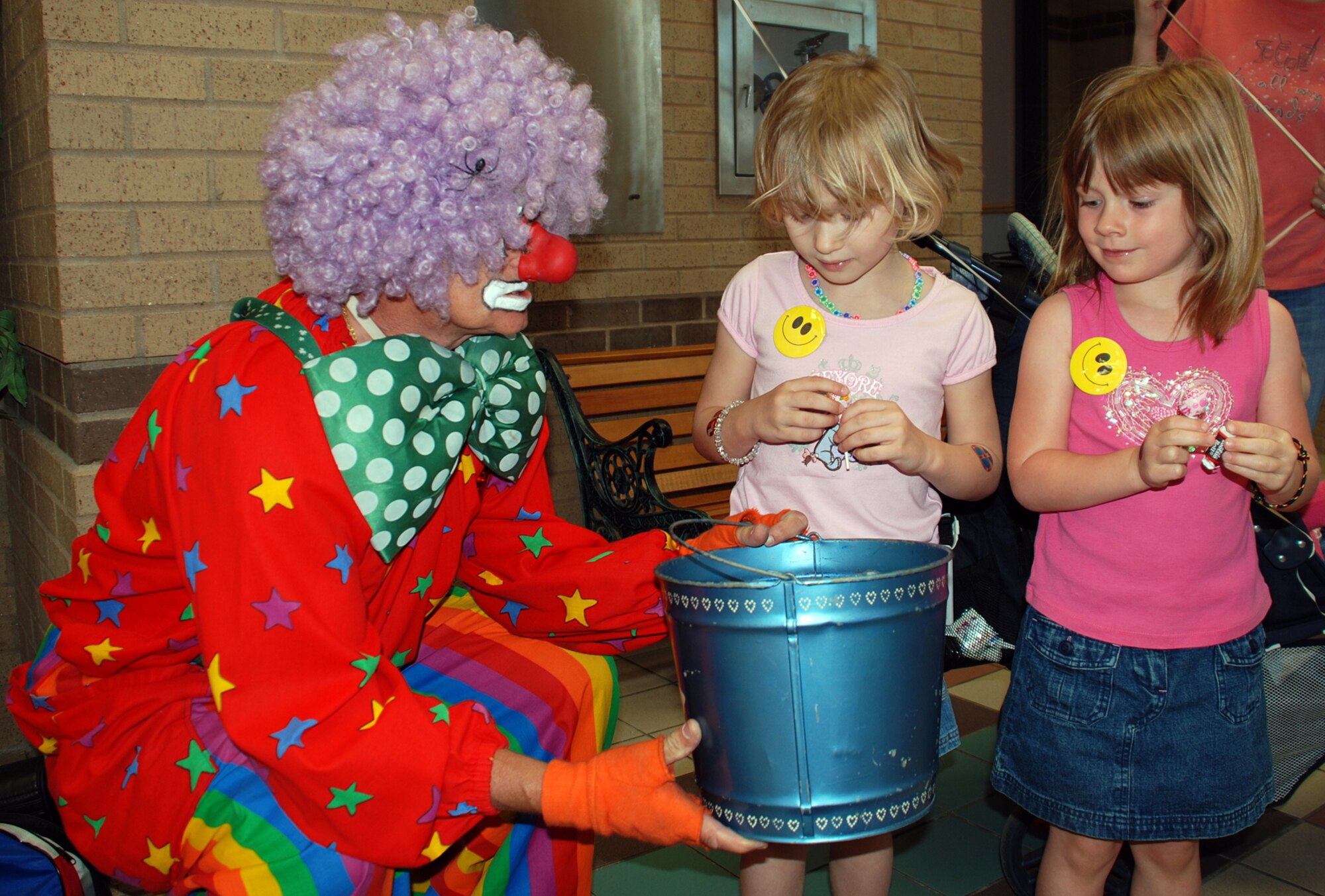A clown offers Sophia Buchanan, center, and Mackenzie Scheidel, right, sweet treats at the ninth annual Family Festival of Fun April 21 at the Robert J. Dole Center here. (Photo by Airman 1st Class Jessica Lockoski)