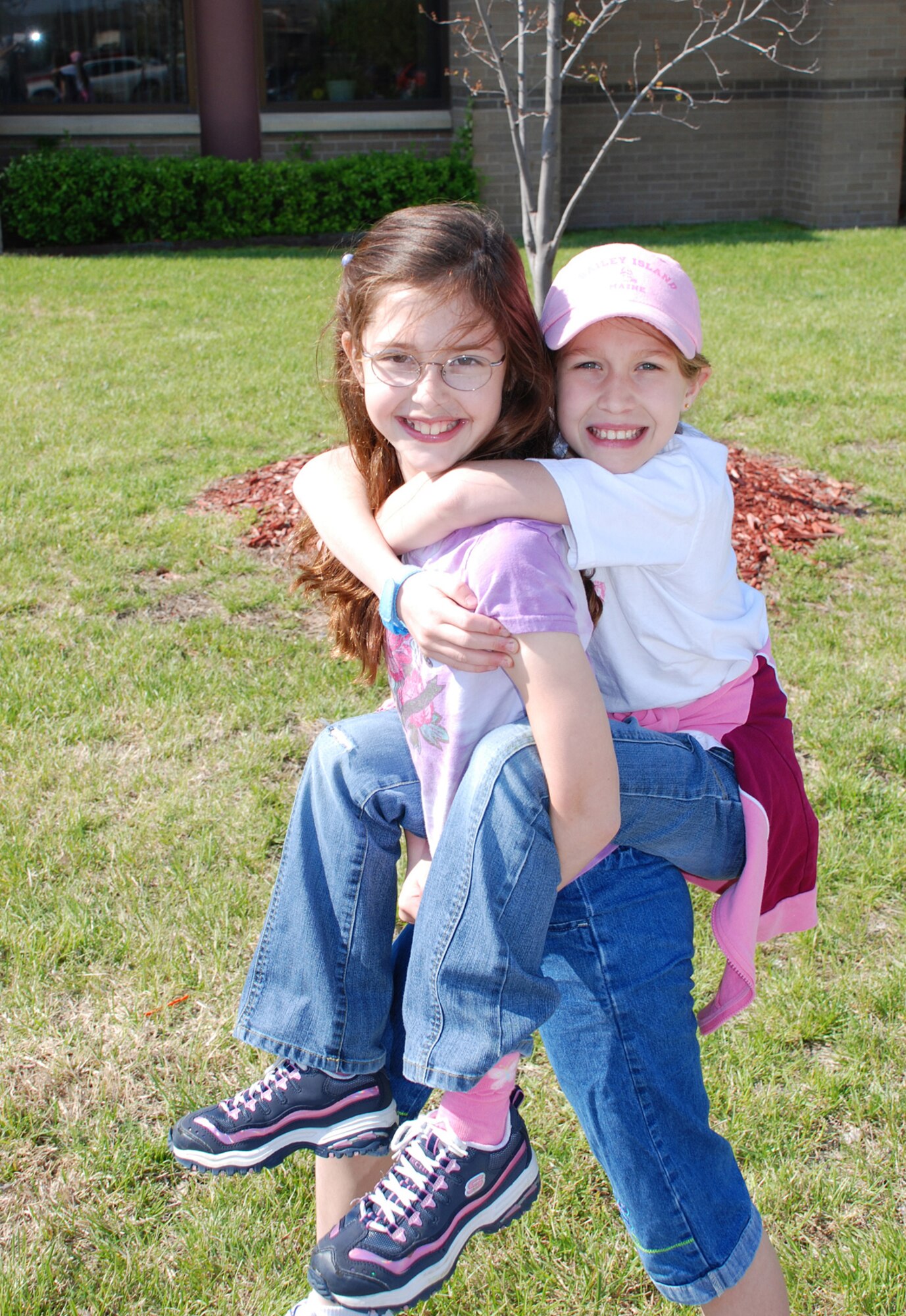 Bailey Fimreite enjoys a piggy-back ride from her friend Taylor Price as they wait for their turn to ride the base fire department’s fire truck in front of the Robert J. Dole Center at the ninth annual Family Festival of Fun here April 21. (Photo by Airman 1st Class Jessica Lockoski)
