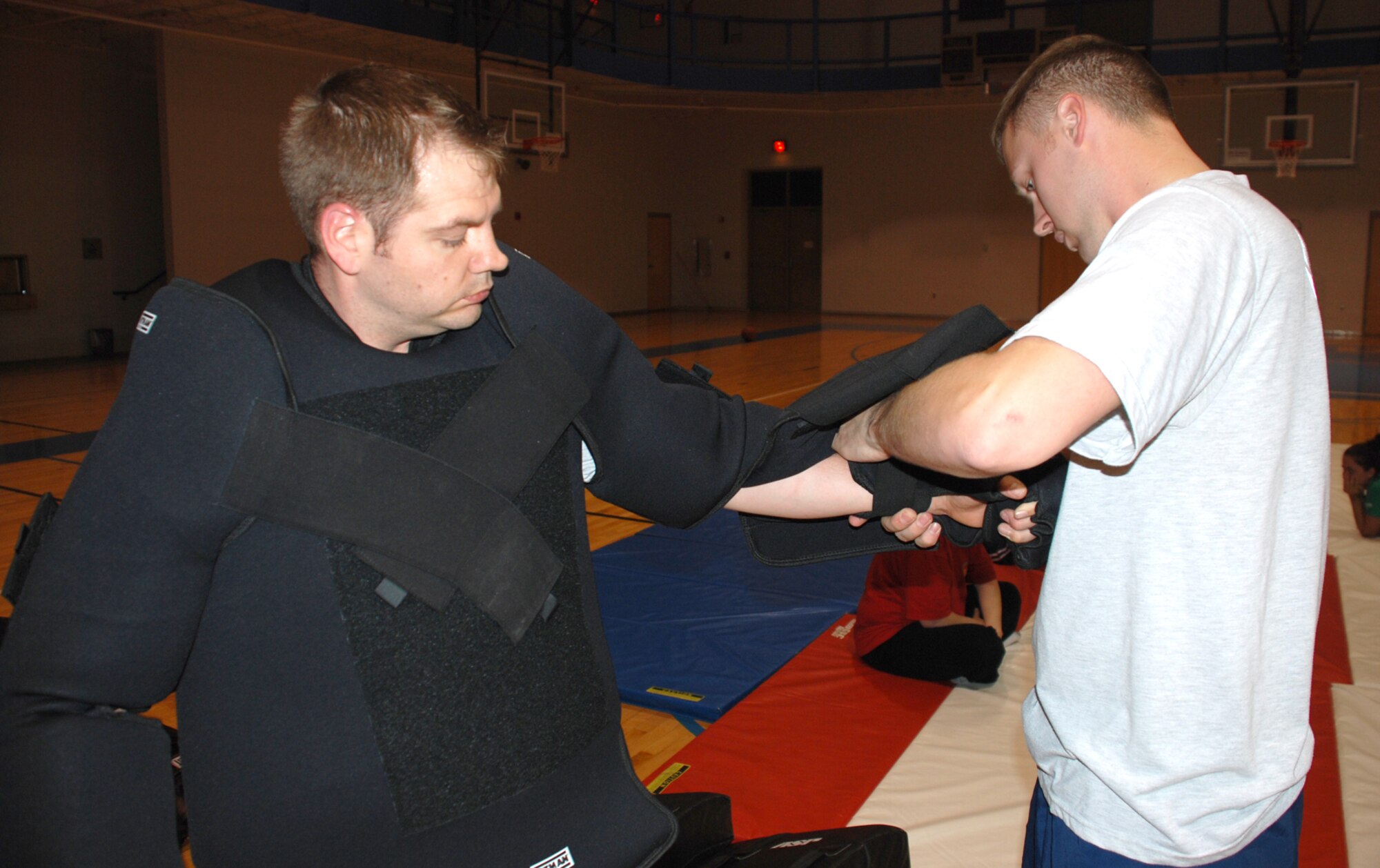 Senior Airman Scott Ury helps Staff Sgt. Sean Gray put on a padded suit, April 18, so he may play the role of an attacker during a women’s self-defense course at the fitness center here. Both Airman Ury and Sergeant Gray are members of the 22nd Security Forces Squadron and women’s self-defense course instructors. (Photo by Airman 1st Class Jessica Lockoski)