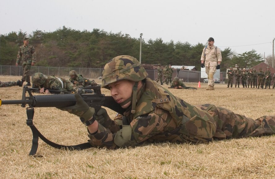 Senior Airman Takao Itoh, a member of the Japan Air Self-Defense Force and a student in the Expeditionary Combat Skills Training, assumes a prone firing position after a high crawl maneuver at Camp Defender on Misawa Air Base, during the three day training April 23-25. The ECST course is designed to prepare troops for deployment. (Photo by Airmen 1st Class Eric Harris) 