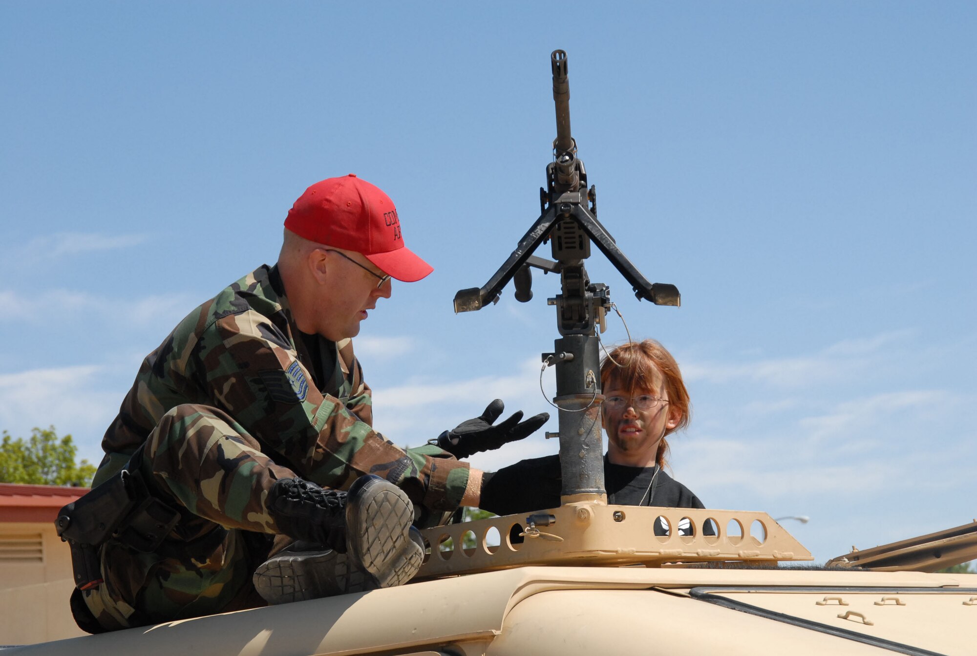 EDWARDS AIR FORCE BASE, Calif. -- Tech. Sgt. Jay Mruk, 95th Security Forces Squadron combat arms noncommissioned officer in charge, shows Megan Brown, 8, parts of an M-240 Bravo installed on a humvee during Operation KUDOS, or Kids Understanding Deployment Operations at Camp Corum here Saturday. (Photo by Airman Mikeal Young)