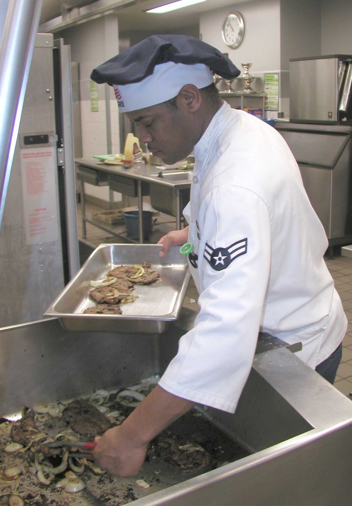 FAIRCHILD AIR FORCE BASE, Wash. – Airman 1st Class Keefer Neal, 92nd Services Squadron, prepares a dinner entrée at the Roger A. Ross Memorial Dining Facility for hungry Survival School students awaiting their first hot meal in a week. (U.S. Air Force photo by Senior Master Sgt. David Walker)