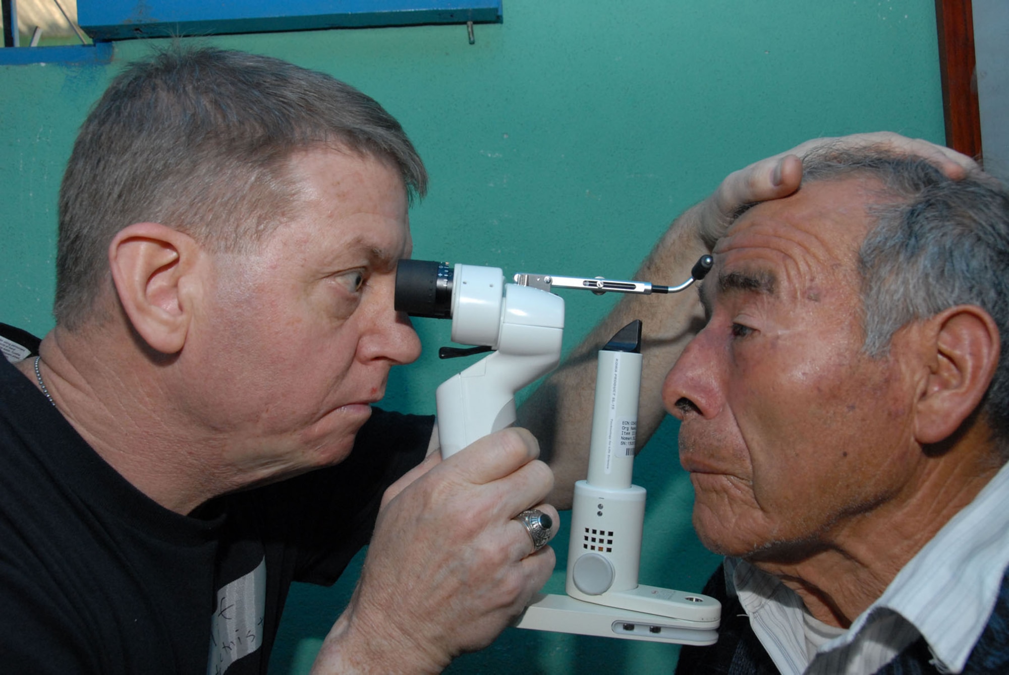 Lt. Col. (Dr.) Clifton Poling, an optometrist with the Air Force Reserve Command's 445th Aerospace Medicine Squadron, Wright Patterson Air Force Base, Ohio, examines the eyes of a Guatemalan patient for cataract evaluation with a hand held slit lamp during the New Horizons Medical Readiness Training Exercise conducted in the San Marcos region April 14-28, 2007. More than 750 pair of presription eyeglasses were given during the exercise. (Air Force photo/ Master Sgt. Chance C. Babin)