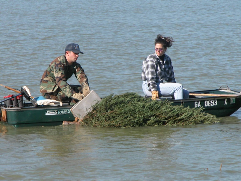 A1C  Gary Yates and  Marilyn Rodgers sink a Christmas tree into Scout Lake to create habitats for fish in the winter of 2004- 2005. U. S. Air Force file photo by Sue Sapp 