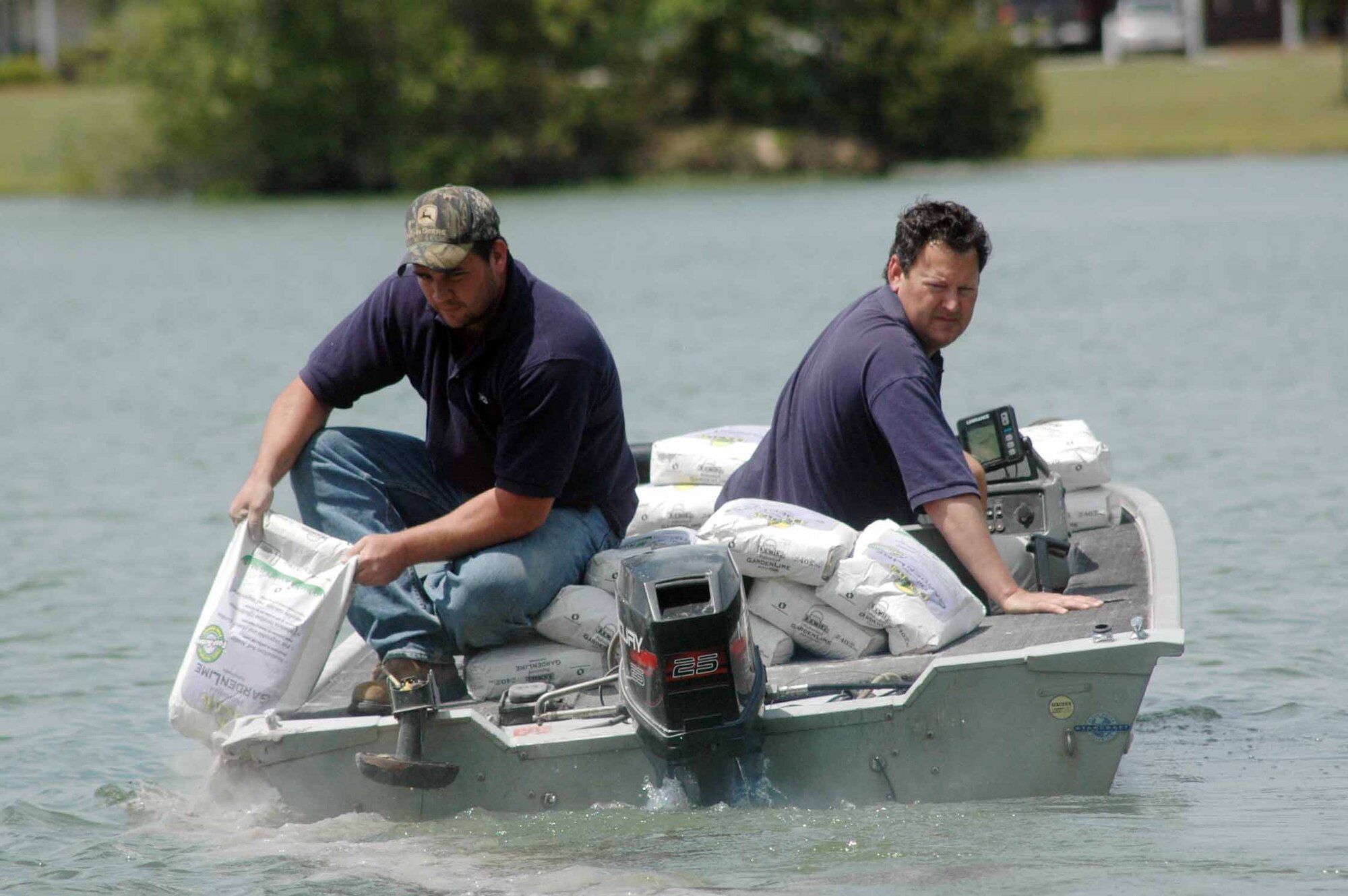 Shane Jones pours lime into Scout Lake as Joel Burke drives the boat.  U. S. Air Force photo by Sue Sapp  