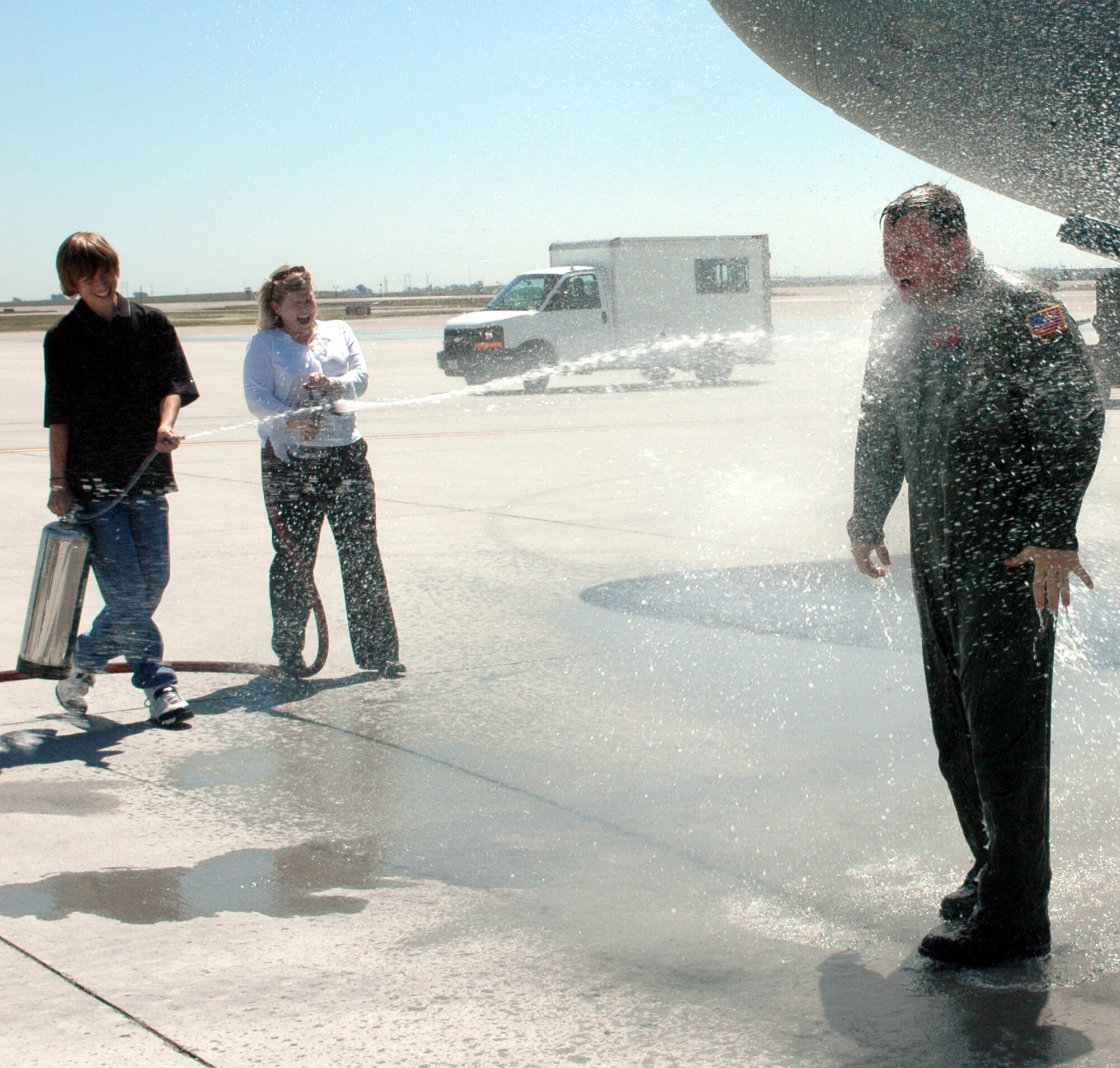 Col. Tom Sharpy, 60th Air Mobility Wing vice commander, is drenched with water by his wife, Lori and son, Dylan, after completing his Fini Flight April 24. Colonel Sharpy is departing Travis mid-May to become wing commander of the 92nd Air Refueling Wing, Fairchild Air Force Base, Wash. (U.S. Air Force photo by Staff Sgt. Candy Knight)