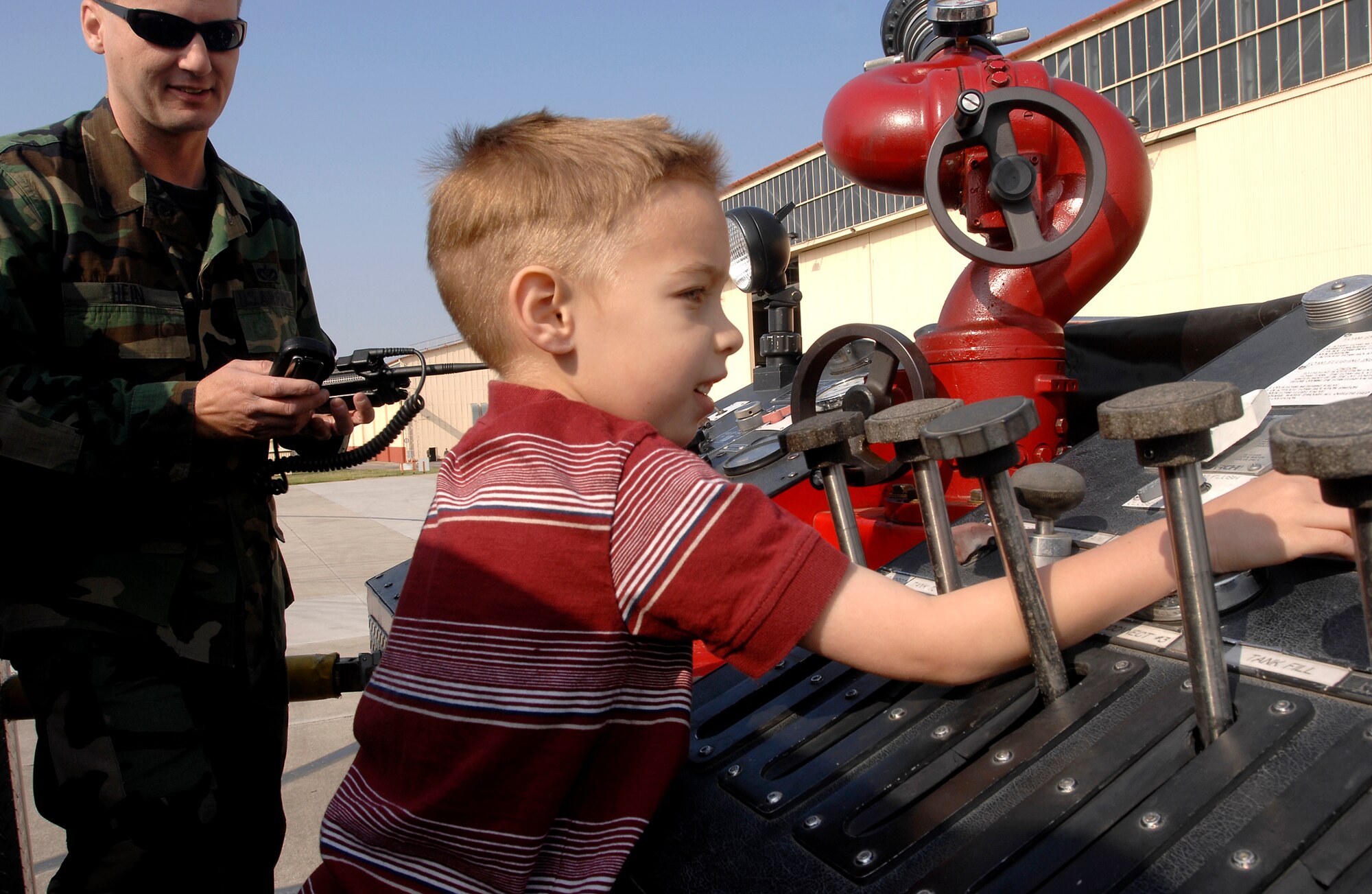 Tech. Sgt. Paul Hein, 31st Civil Engineer Squadron, shows Tate Michael Mooney how to control a fire truck during the Children’s Deployment. Children received hands on experience with the deployment process April 19. Photo by Airman 1st Class Liliana Moreno