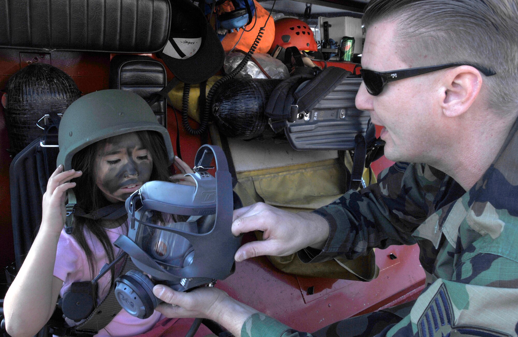 Tech. Sgt. Paul Hein, 31st Civil Engineer Squadron, shows Marrissa Mandregan the inside of a gas mask and instructs her how wear it during the Children’s Deployment April 19. Photo by Airman 1st Class Liliana Moreno