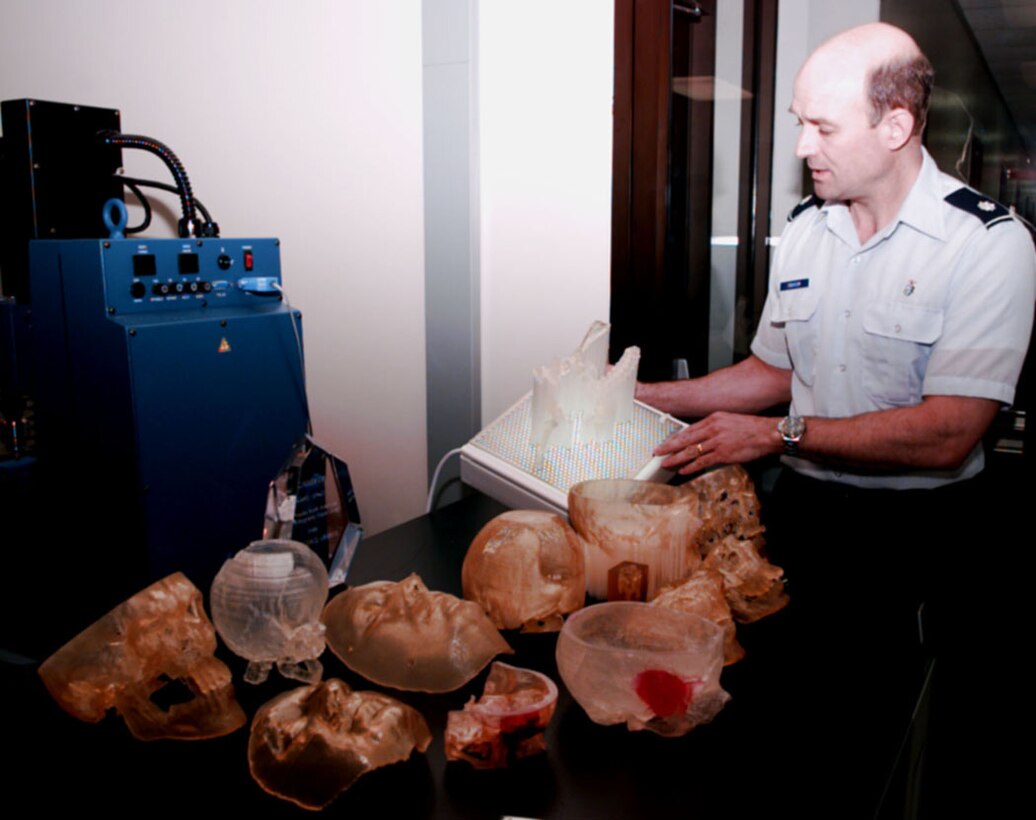 Dr. (Lt. Col.) Doug Erickson holds a tray of epoxy polymer bars a stereo lithography machine uses to create human bone structures such as those on the table before him. The Air Force's Wilford Hall Medical Center in San Antonio, Texas, is DoD's only medical facility with the capability. Erickson foresees a time when medics in the field will digitally scan wounded soldiers and transmit the images back to Wilford Hall. There, a model will be built for surgeons to study until their patient arrives. "The impact on medical readiness will be significant," Erickson said. Douglas J. Gillert 