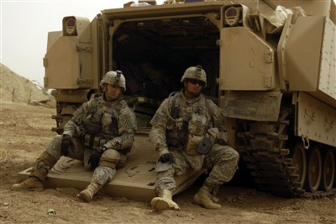 U.S. Army Pvt. Jason Douglas and Pfc. Awa Gasper wait at Patrol Base Cashe, Iraq, to load up into their Bradley vehicle to patrol back to Command Out Post Cahill Salman Pak, Iraq on April 24, 2007.  Douglas and Gasper are assigned to 2nd Platoon, Alpha Company, 1st Battalion, 15th Infantry, 3rd Brigade, 3rd Infantry Division.  