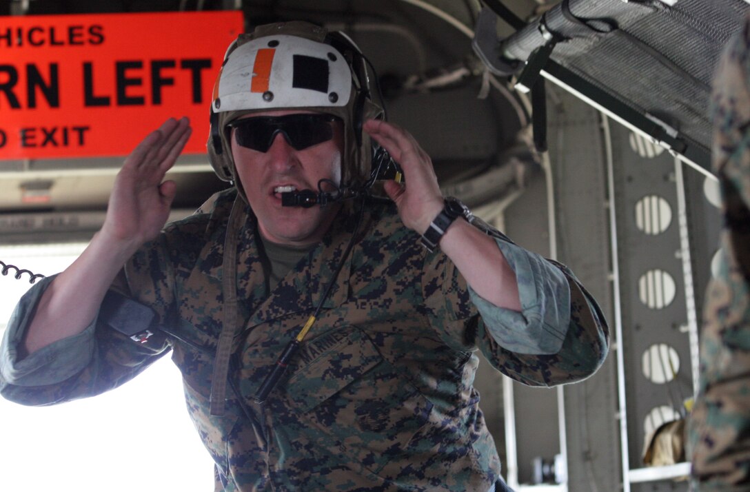 Sgt. Brian J. Mohr, assistant jumpmaster for the training exercise with 2nd Reconnaissance Battalion, 2nd Marine Division, uses hand signals to communicate instructions to a group of Marines preparing to parachute 2,000 feet from a CH-53E Super Stallion helicopter. ?The signals are verbally and physically repeated inside the aircraft, so each jumper knows what?s happening,? said Mohr.