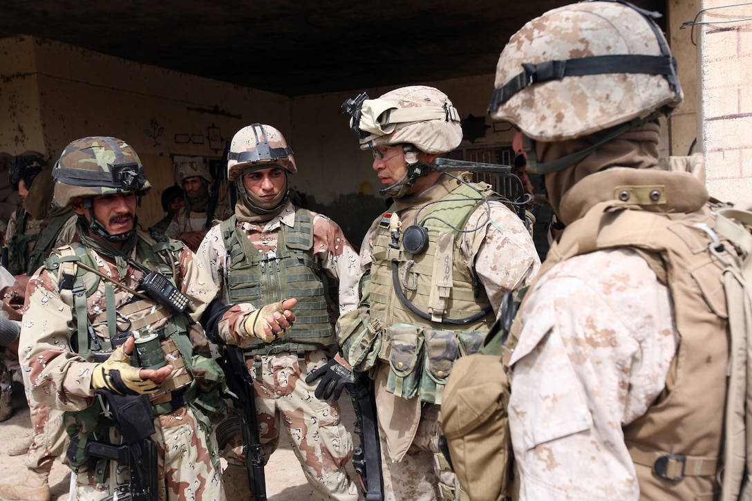 Gunnery Sgt. Fernando L. Llanos, 33, from Queens, N.Y., listens to a mission brief given by an Iraqi Army soldier from 1st Brigade, 3rd Battalion, 1st Iraqi Army Division. Llanos is a advisor with the Military Transition Team, which originated from 3rd Battalion, 6th Marine Regiment. As the senior advisor for Company 2 he embeds with the Iraqi Army to help make the unit self-sustainable and capable of independent combat operations.