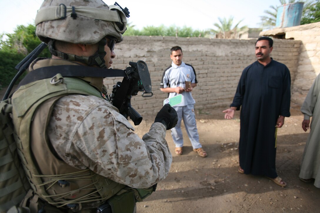 Gunnery Sgt. Fernando L. Llanos, 33, from Queens, N.Y., checks the identification of an Iraqi civilian while on patrol with soldiers from 1st Brigade, 3rd Battalion, 1st Iraqi Army Division.  Taking charge and setting the right example are important qualities in his duties as the senior advisor for Company 2. He is part of the Military Transition Team, which originated from 3rd Battalion, 6th Marine Regiment.