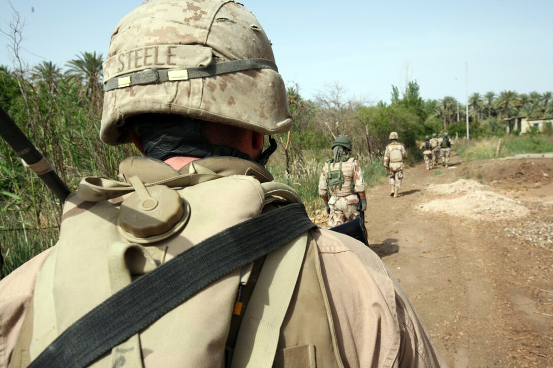 A squad of soldiers from 1st Brigade, 3rd Battalion, 1st Iraqi Army Division patrol under the watchful eyes of Lance Cpl. Eric R. Steele, 21, from Elkin, N.C. Steele is the junior advisor for these soldiers of Company 2. He is part of the Military Transition Team, which originated from 3rd Battalion, 6th Marine Regiment. As an advisor he lives, trains and patrols with the Iraqis.