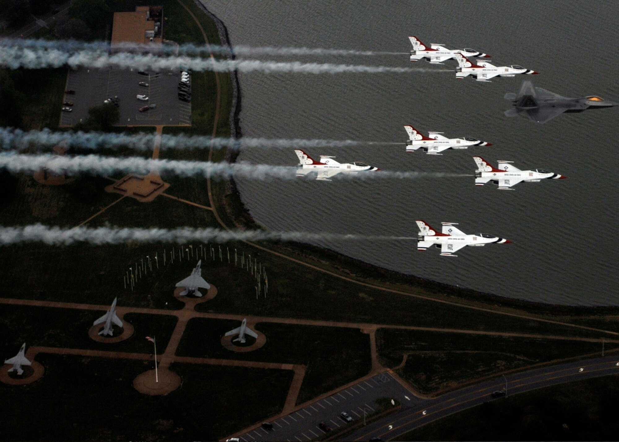 Maj. Max Moga, F-22A Raptor demonstration pilot, leads six Thunderbird F-16s in formation over Freedom park at Langley Air Force Base, Va., during their practice day April 27 for the Airpower Over Hampton Roads air show scheduled April 28-29. This year the Thunderbirds and the F-22 demonstrations commemorate the 60th Anniversary of the United States Air Force. (U.S. Air Force photograph/Tech. Sgt. Justin D. Pyle)