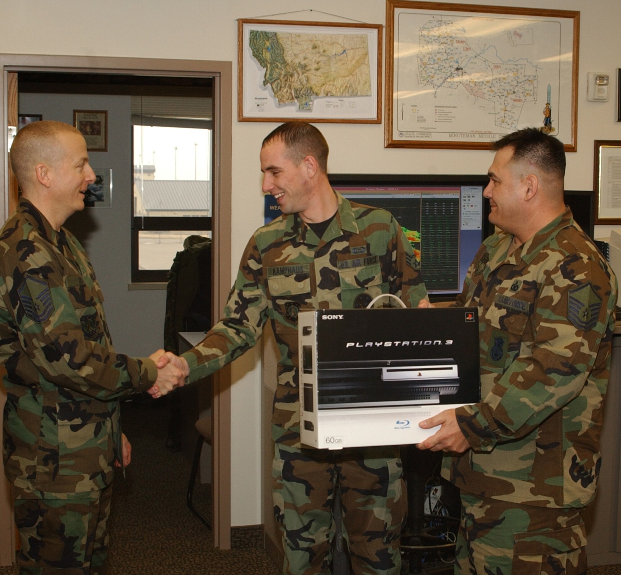 Master Sgt. Tim Hezel, 341st Missile Maintenance Squadron, (left), and Master Sgt. Gene Miller, 341st Missile Security Forces Squadron, (right), present Senior Airman James Kamphaus, 341st Operations Support Squadron, with a Playstation 3 at the Weather Operations Flight, Feb. 6.  Airman Kamphaus won the entertainment system in a fundraiser drawing sponsored by the Enlisted Dining Out committee. (U.S. Air Force photo/ 2nd Lt. Justin Brockhoff)