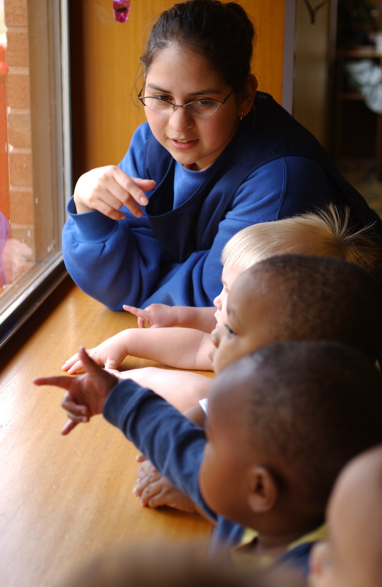 Jennifer McClure, child development program assistant, looks out a window with youth in her classroom at Child Development Center East on RAF Lakenheath April 26. The program houses children 6 weeks of age to just before school age. (U.S. photo by Staff Sgt. Nicholasa Reed)