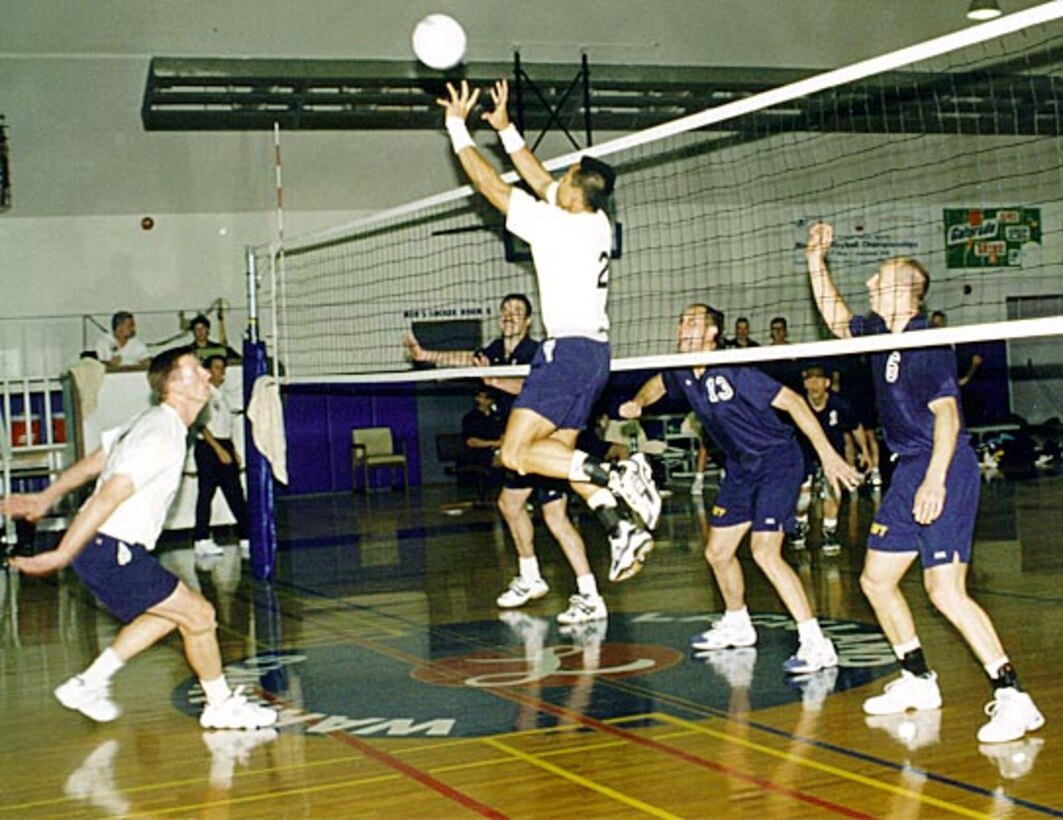 Air Force setter Sammy Nimchaimanathan, in the air, sets up a return. Middle blocker John Napier, left, keeps an eye on the ball during the first match against the Navy at the 1999 Armed Forces Men's Volleyball Championships. Navy blockers, from right, Jeffrey Ernsberger, Christian Fassari and Scott Ruston await the return. Robbin Cresswell 