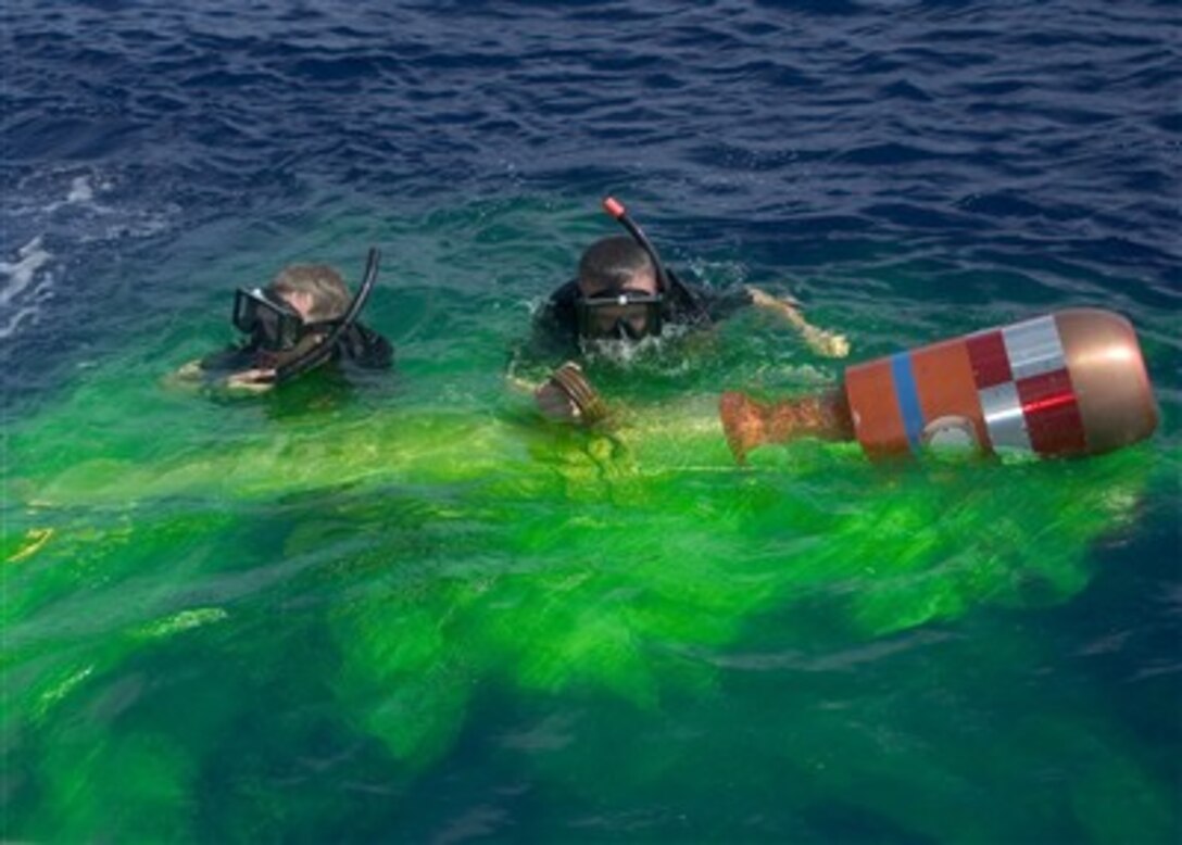 U.S. Navy Petty Officers 3rd Class Tyler Nilsson (left) and Matthew Loeffler recover a practice torpedo in the Pacific Ocean on April 19, 2007.  The torpedo was deployed from an SH-60B Seahawk helicopter from Detachment 6, Helicopter Squadron Light 51 during an exercise.  Nilsson and Loeffler are rescue swimmers aboard the Arleigh Burke-class guided-missile destroyer USS Lassen (DDG 82).  
