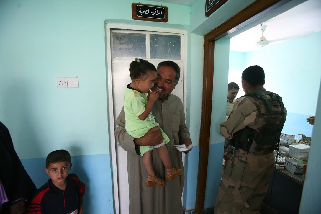 An Iraqi civilian shares a laugh with his daughter while waiting for his medication. He was taking advantage of the free medical care being provided by soldiers from the 1st Brigade, 3rd Battalion, 1st Iraqi Army Division. The IA soldiers were running a combined medical engagement with some advice from the Military Transition Team, a team that originated from 3rd Battalion, 6th Marine Regiment.