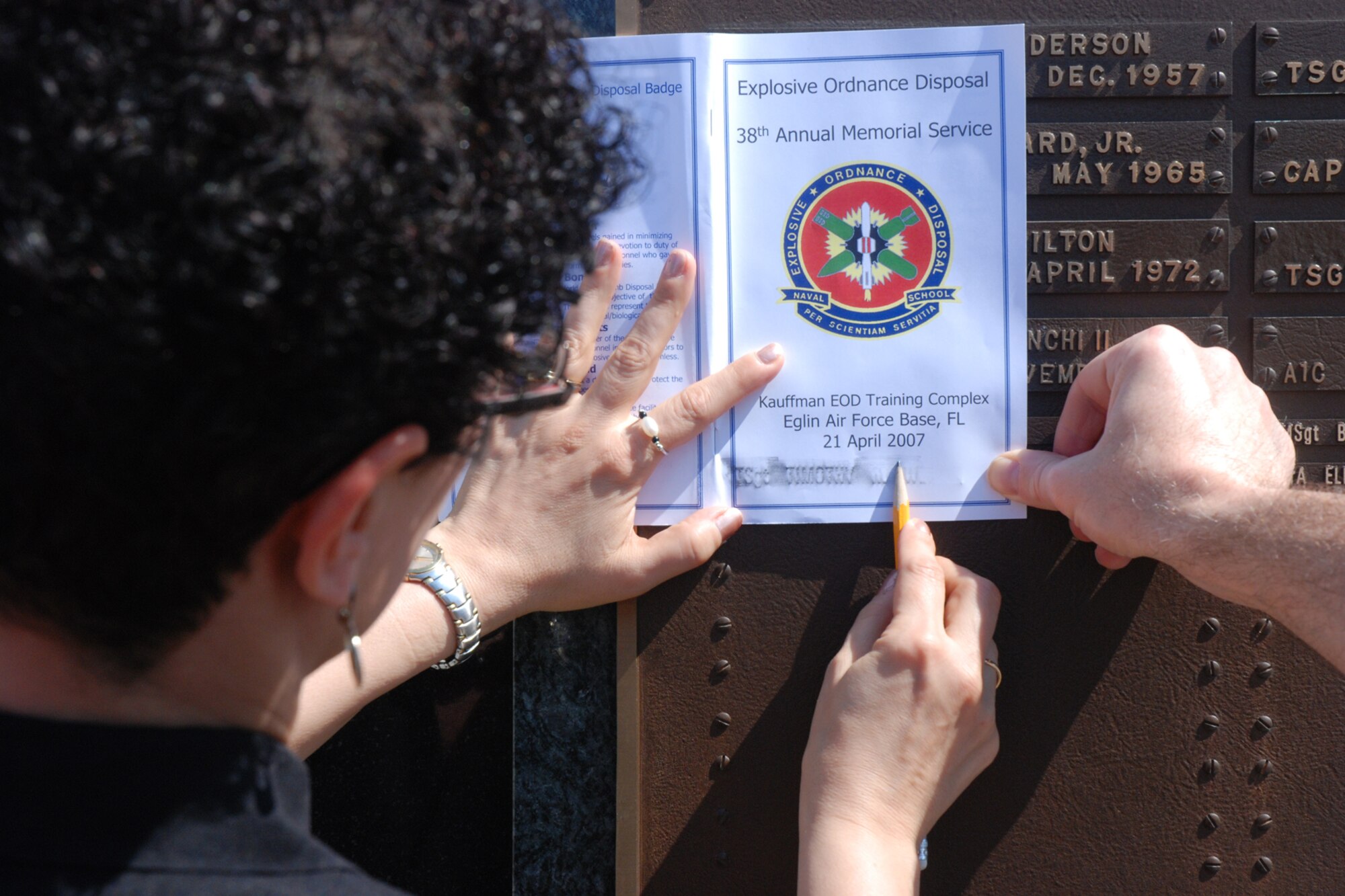 EGLIN AIR FORCE BASE, Fla. -- Karyn Plante, sister to Tech. Sgt. Timothy R. Weiner, etches his name on the cover of a program during the Explosive Ordnance Disposal 38th Annual Memorial Service at the Kauffman EOD Training Complex April 21. Sergeant Weiner was one of three Airmen killed by an improvised explosive device in Baghdad, Iraq, Jan. 7, 2007. The ceremony memorialized 14 names of Soldiers, Sailors, Airmen, Marines and Coast Guardsmen who have sacrificed their lives during EOD missions. Those names will bring the total to 215 names inscribed on the bronze tablets of the memorial. (U.S. Air Force photo by Staff Sgt. Mike Meares)